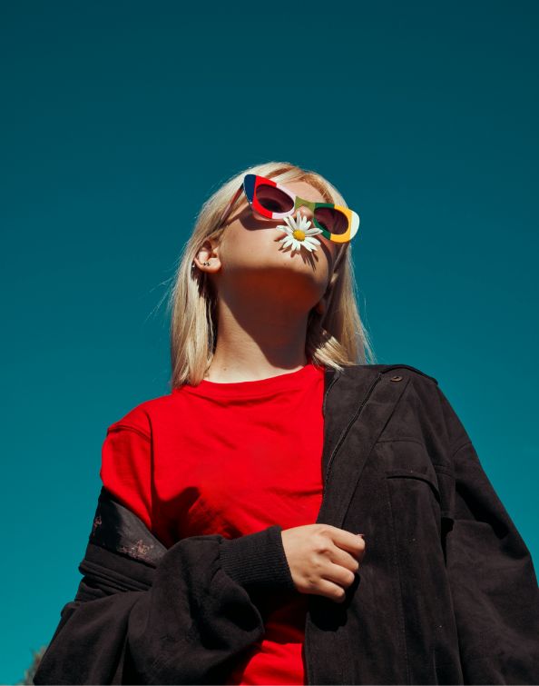 young woman wearing colorful sunglasses and bright red shirt